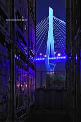 blue_pylon Durch gestapelte Reihen von Containern schweift der nächtliche Blick auf den blau angestrahlten Pylon der Köhlbrandbrücke in Hamburg.