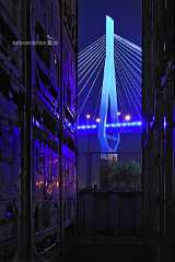 blue_pylon Durch gestapelte Reihen von Containern schweift der nächtliche Blick auf den blau angestrahlten Pylon der Köhlbrandbrücke in Hamburg.