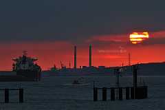 darksun Kurz vor Sonnenuntergang an der Elbe bei Wedel vor Hamburg. Die Sonne schaut als gleißender Ball hinter den grauen Wolken vor einem blutrotem Himmel hervor. Das...