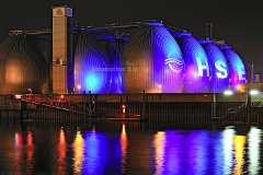 eierfabrik Violett beleuchtete Fauleier des Klärwerks Köhlbrandhöft in Hamburg spiegeln sich im ruhigen Wasser der Elbe.