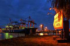 tankschiffhafen Ein Containerschiff der Reederei MOL liegt zur blauen Stunde am Kai unter Containerbrücken. Im Vordergrund ein großes, von 2 Strahlern beleuchtetes Schild.