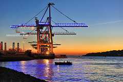 bootstörn Ein kleines Boot liegt in Hamburg auf der Elbe vor Containerbrücken. Der Himmel hat einen schönen Farbverlauf vom Abendrot zum blau der einsetzenden Dämmerung....