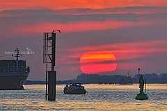 elbverkehr Eine malerische Szenerie auf der Elbe: die tiefstehende Sonne als großer roter Ball wird von ein Dalben mit einem Schifffahrtszeichen und eine grünen...