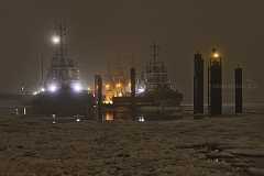 schlepperstation Mehrere Schlepper liegen im nebligen Hafen an der Schlepperstation. Auf dem Wasser treiben Eisschollen. Einzelne Lichter durchdringen den Nebel.