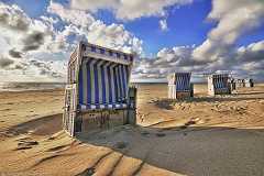 strandkorb Ein sonniger Strandtag auf Sylt. Mehrere leere Strandkörbe stehen im Sand am Strand von Kampen auf Sylt. Malerische weiße Wolken ziehen am blauen Himmel vorbei.