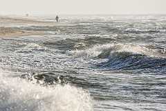 strandspaziergang Strandspaziergang auf Sylt bei windigem Wetter und Sonnenschein. Die weiße Gischt tanzt auf den Wellen der Nordsee die sich am Strand brechen und glitzert im...