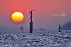 sundown_elbe Auf der Elbe bei Hamburg kurz vor Sonnenuntergang. Ein Dalben mit Schifffahrtszeichen und eine grüne Leuchtboje bilden einen stimmungsvollen Vordergrund zu dem...