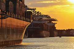 abendsonne Im Hafen Hamburg führt der abendliche Blick nach Sonnenuntergang bei goldgelb farbenem Himmel im Containerhafen an der mächtigen Wand eines Containerschiffs...